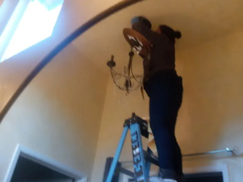 Electrician installing a chandelier in a Redding residence